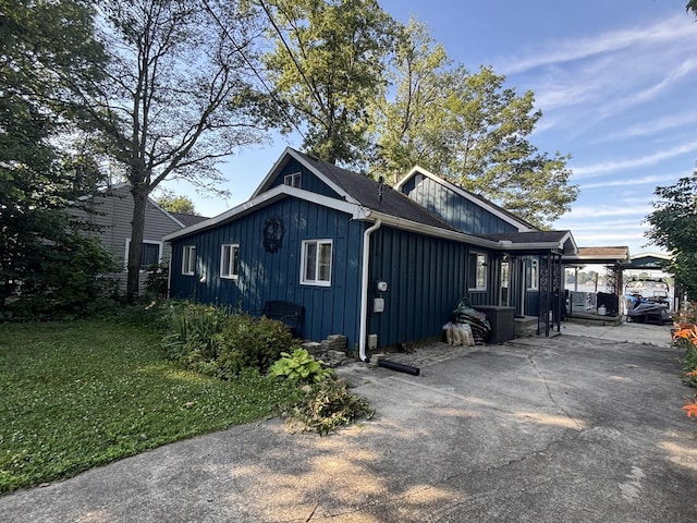 9029 Maple St, Huntsville, OH 43324 - view of side of home featuring board and batten siding, concrete driveway, and a yard