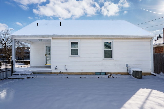 snow covered back of property with a porch, fence, and central air condition unit