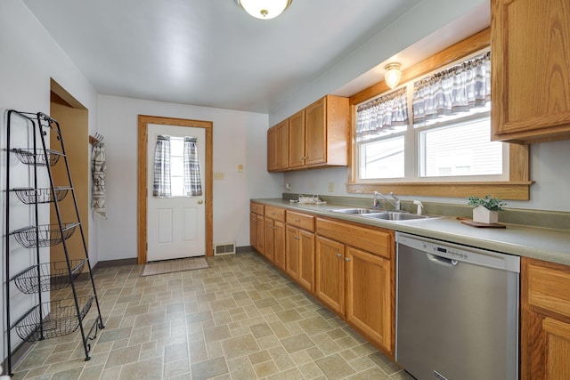 kitchen featuring light countertops, visible vents, stainless steel dishwasher, a sink, and baseboards