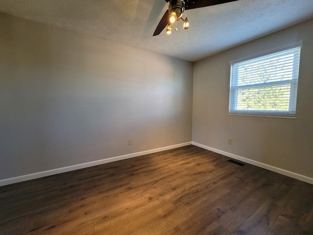 unfurnished room featuring visible vents, baseboards, a textured ceiling, and dark wood finished floors