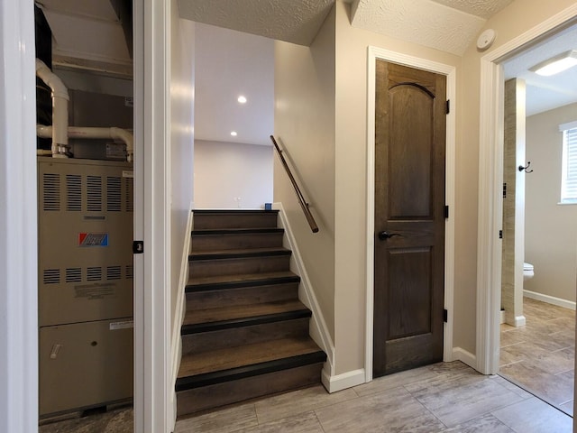 stairway with recessed lighting, a textured ceiling, and baseboards