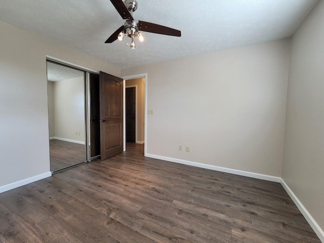 unfurnished bedroom featuring baseboards, a closet, a textured ceiling, a ceiling fan, and dark wood-style flooring