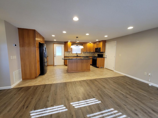 kitchen featuring visible vents, a sink, black appliances, dark countertops, and backsplash