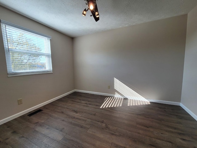 unfurnished room with baseboards, visible vents, dark wood-style flooring, ceiling fan, and a textured ceiling