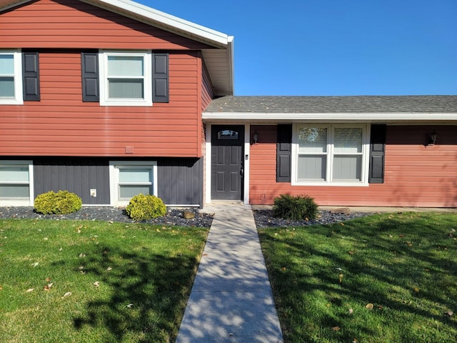 tri-level home with a front lawn and roof with shingles