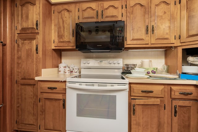 106 Westview Dr, Arcanum, OH 45304 - kitchen with black microwave, white electric stove, tasteful backsplash, light countertops, and brown cabinetry