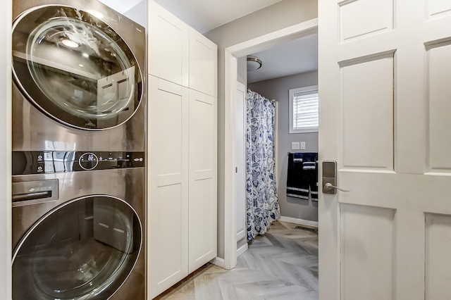 laundry room with cabinet space, baseboards, visible vents, and stacked washer and clothes dryer