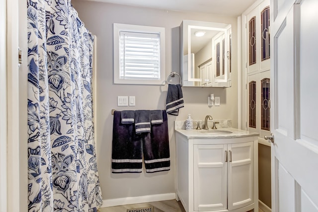 bathroom featuring curtained shower, vanity, and baseboards