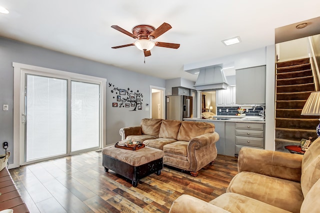 living room featuring dark wood-style floors, ceiling fan, and stairway