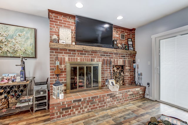 living room with a brick fireplace, wood finished floors, and recessed lighting