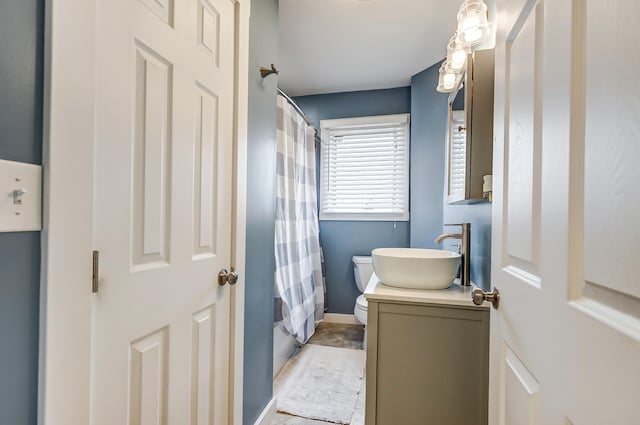 bathroom featuring shower / bathtub combination with curtain, baseboards, vanity, and toilet