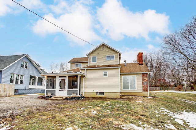 rear view of property with a lawn, a chimney, fence, and a sunroom