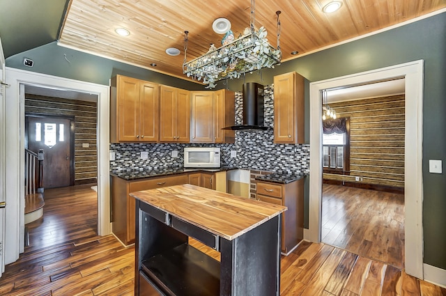 kitchen featuring a center island, dark hardwood / wood-style floors, wood counters, and wall chimney exhaust hood