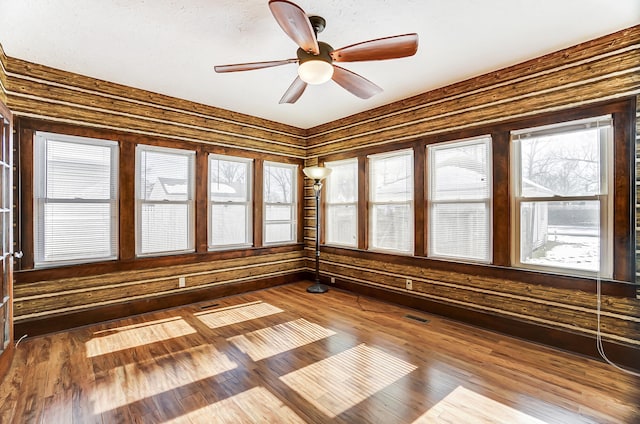 unfurnished sunroom with ceiling fan and a healthy amount of sunlight