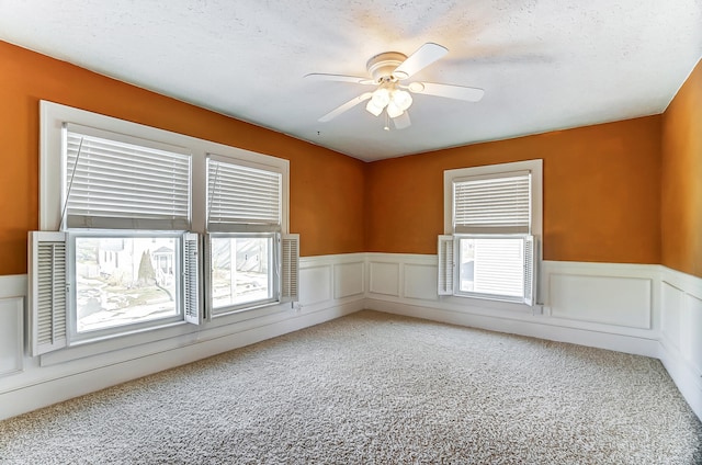 empty room with a textured ceiling, ceiling fan, and carpet flooring