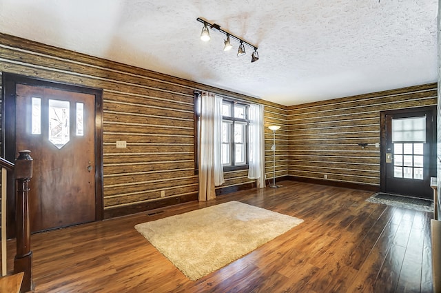 foyer with dark hardwood / wood-style flooring, track lighting, a textured ceiling, and wood walls