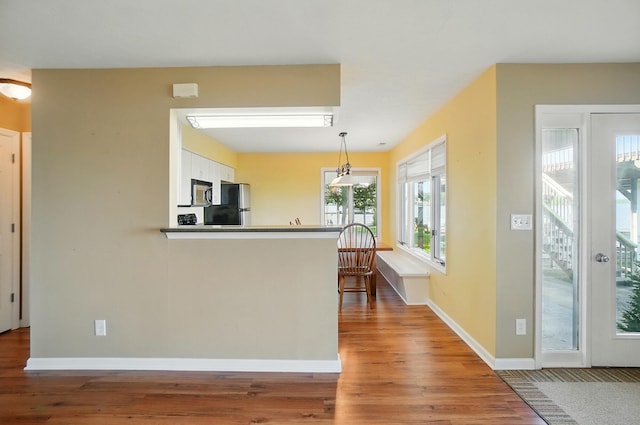 9113 Lake Ave, Huntsville, OH 43324 - kitchen featuring freestanding refrigerator, wood finished floors, white cabinetry, hanging light fixtures, and stainless steel microwave