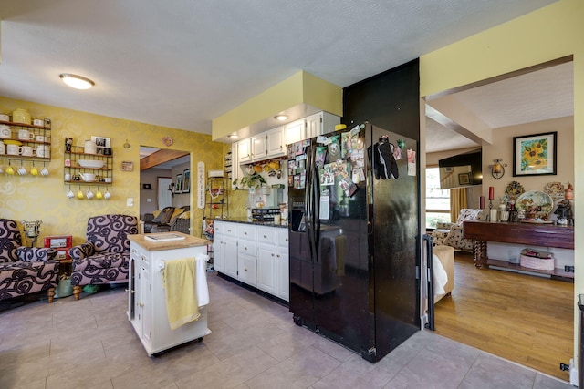 kitchen with white cabinetry, light tile patterned floors, a textured ceiling, and black fridge