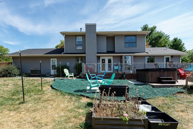 back of property featuring a hot tub, a wooden deck, and a yard