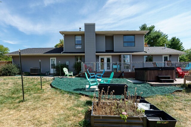 back of house with a wooden deck, a yard, and a hot tub