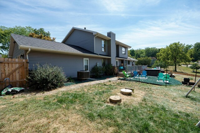 rear view of house featuring a wooden deck, a yard, central AC unit, and a jacuzzi