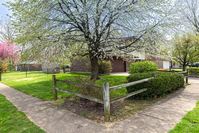 view of property's community featuring an attached garage, driveway, a yard, and fence private yard
