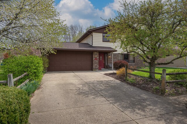 view of front of property featuring fence, a shingled roof, an attached garage, driveway, and brick siding