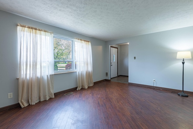 unfurnished living room featuring baseboards, hardwood / wood-style floors, visible vents, and a textured ceiling