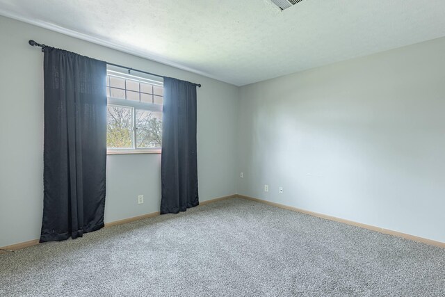 spare room featuring visible vents, carpet flooring, and baseboards