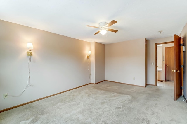 spare room featuring light colored carpet, ceiling fan, and baseboards