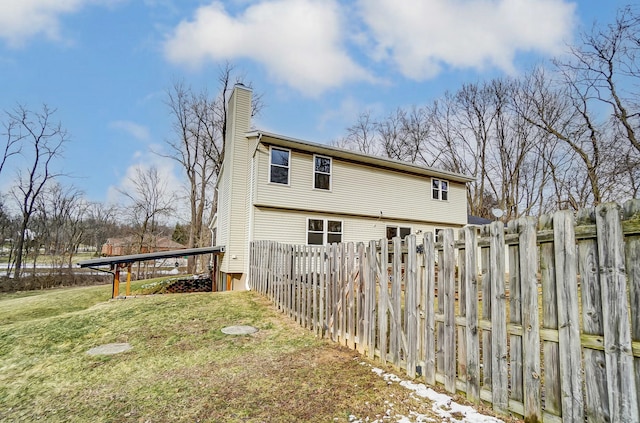 rear view of property featuring a chimney and a yard