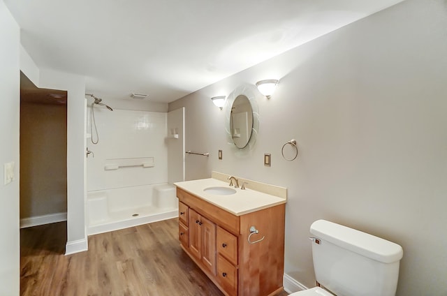 bathroom featuring vanity, wood finished floors, a shower stall, and toilet