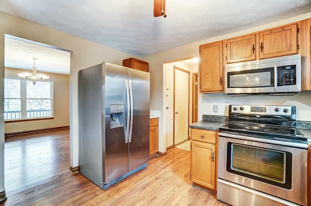 kitchen featuring dark countertops, light wood-style floors, baseboards, and appliances with stainless steel finishes