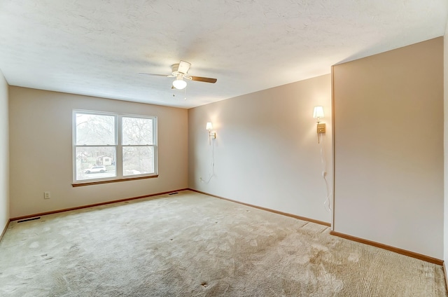 empty room with visible vents, a ceiling fan, light carpet, a textured ceiling, and baseboards