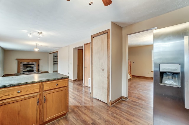 kitchen featuring dark countertops, a brick fireplace, open floor plan, and light wood finished floors