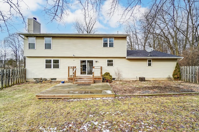 rear view of house featuring a chimney, fence, a lawn, and a wooden deck