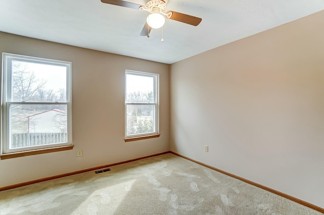 empty room featuring light carpet, visible vents, baseboards, and ceiling fan