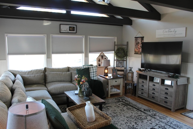 living room with a wainscoted wall, lofted ceiling with beams, and wood finished floors