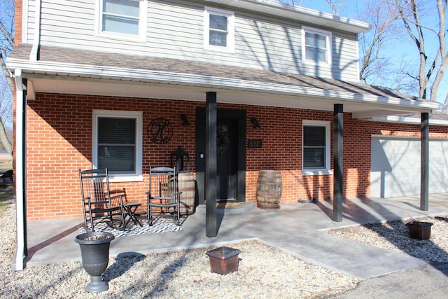 exterior space featuring brick siding, a porch, and an attached garage
