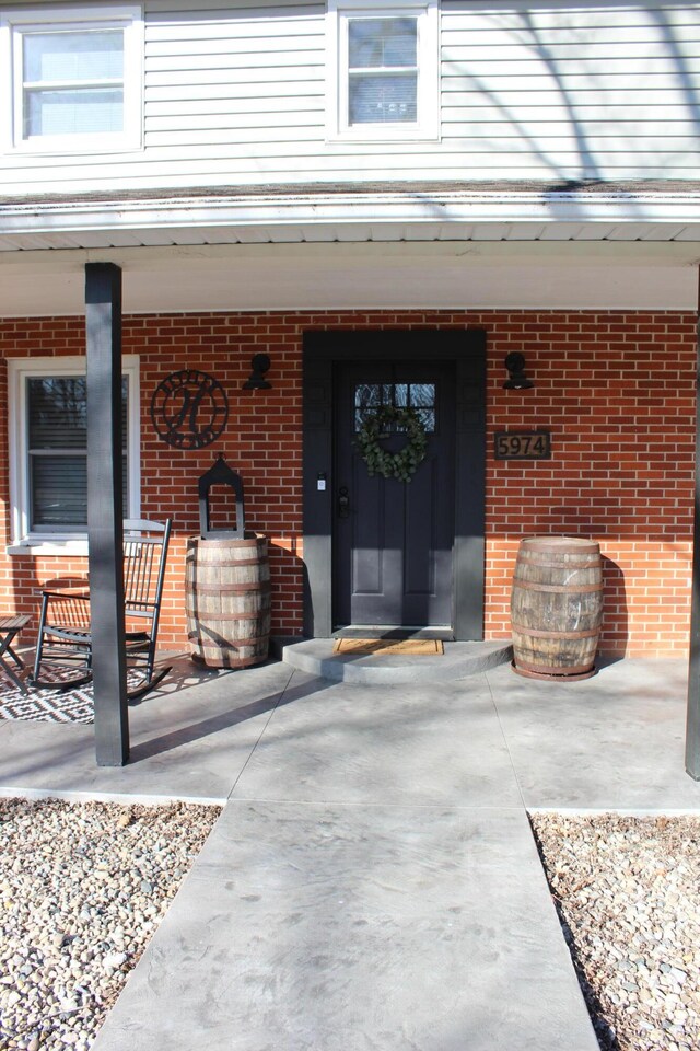 doorway to property with brick siding and a porch