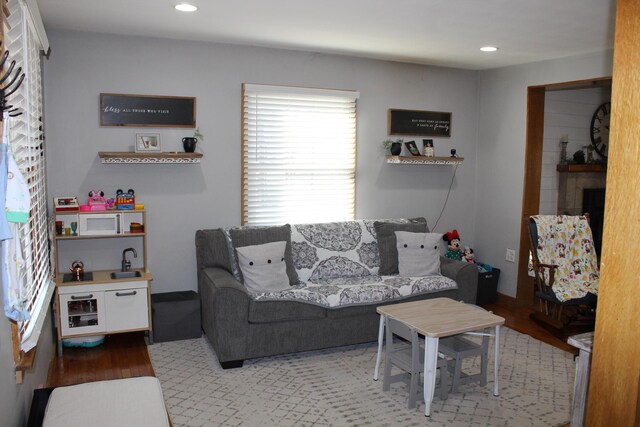 living area with recessed lighting, a fireplace, and wood finished floors