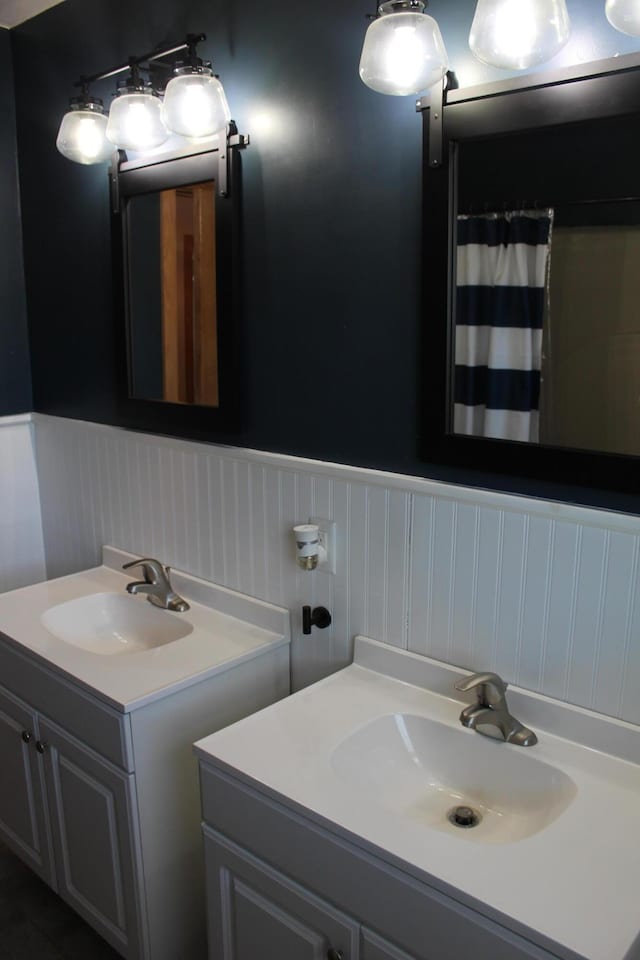 full bathroom featuring vanity, curtained shower, and a wainscoted wall