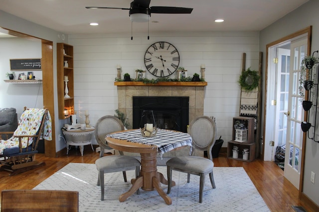 dining room with a tiled fireplace, recessed lighting, ceiling fan, and wood finished floors