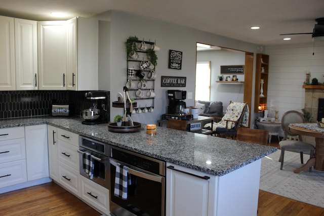 kitchen with oven, wood finished floors, a peninsula, and open floor plan