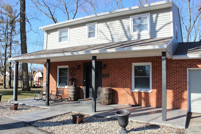 view of front of property featuring brick siding, a porch, and a shingled roof