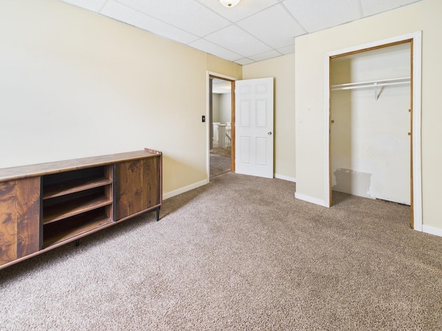 unfurnished bedroom with a closet, carpet flooring, a drop ceiling, and baseboards