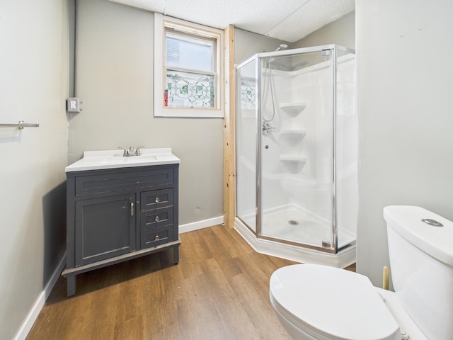 full bath with vanity, baseboards, a stall shower, toilet, and wood finished floors