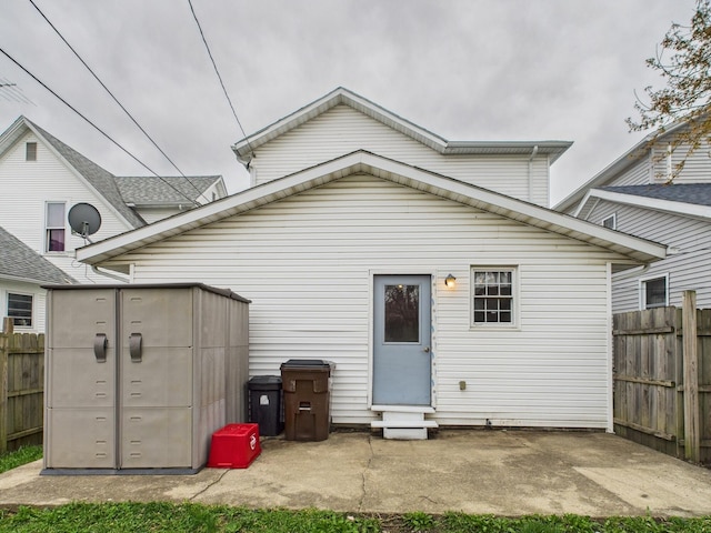 back of property featuring a patio, an outbuilding, and fence