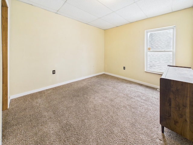 empty room featuring carpet flooring, a paneled ceiling, and baseboards