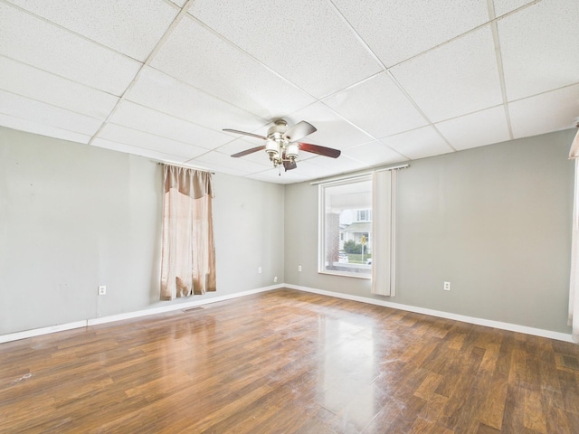 empty room with ceiling fan, a paneled ceiling, and wood finished floors